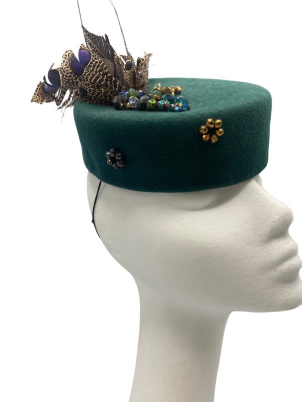 Stunning forest green felt pillbox with an array of beautiful feathers. This headpiece has some beaded detail throughout the base also.